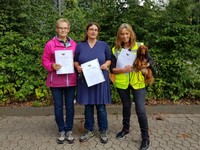 Drei Hundeführer mit Urkunden für E-Prüfung.